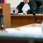 Judge at desk in courtroom with microphones visible