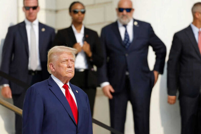2545412917 Man in blue suit with people in background standing