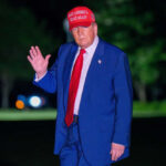 Man in suit wearing red hat outside at night
