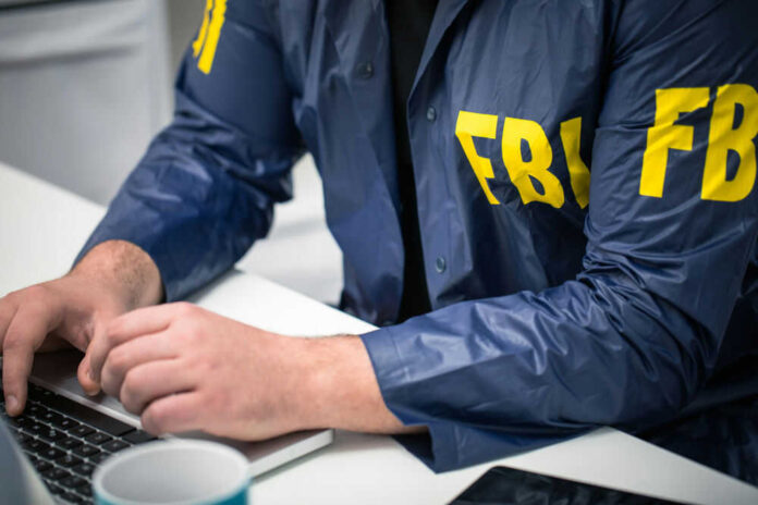 629482379 Person in FBI jacket using a laptop