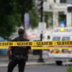 Police officers near a crime scene marked by caution tape