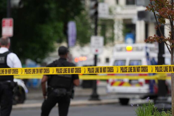 shutterstock_2622588825.jpg Police officers near a crime scene marked by caution tape