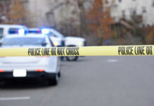 Police tape blocking road with parked police vehicles