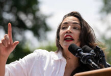 Person speaking passionately at outdoor event with microphones