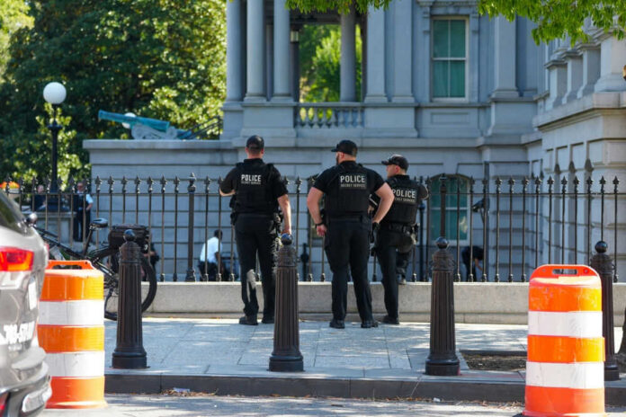 Three police officers in dark uniforms standing outside building
