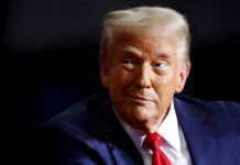 Person wearing suit and red tie looking sideways