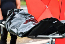 Person carrying body bag on stretcher outdoors