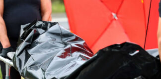 Person carrying body bag on stretcher outdoors