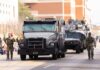 Military vehicles and personnel in a parade on a city street