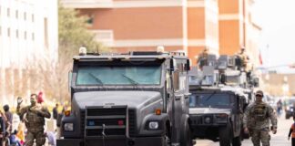 Military vehicles and personnel in a parade on a city street