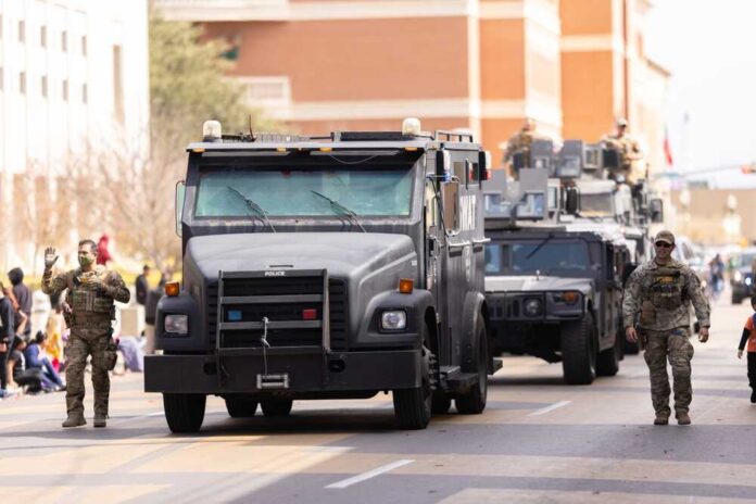 Military vehicles and personnel in a parade on a city street
