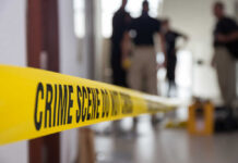 Yellow crime scene tape with blurred figures in the background