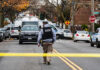 Law enforcement officer walking towards a crime scene marked by police tape