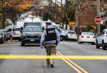 Law enforcement officer walking towards a crime scene marked by police tape
