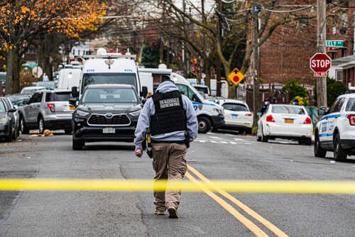 Law enforcement officer walking towards a crime scene marked by police tape