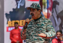 Man in camouflage uniform speaking at event outdoors