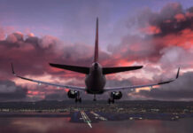 Airplane approaching airport runway at sunset sky